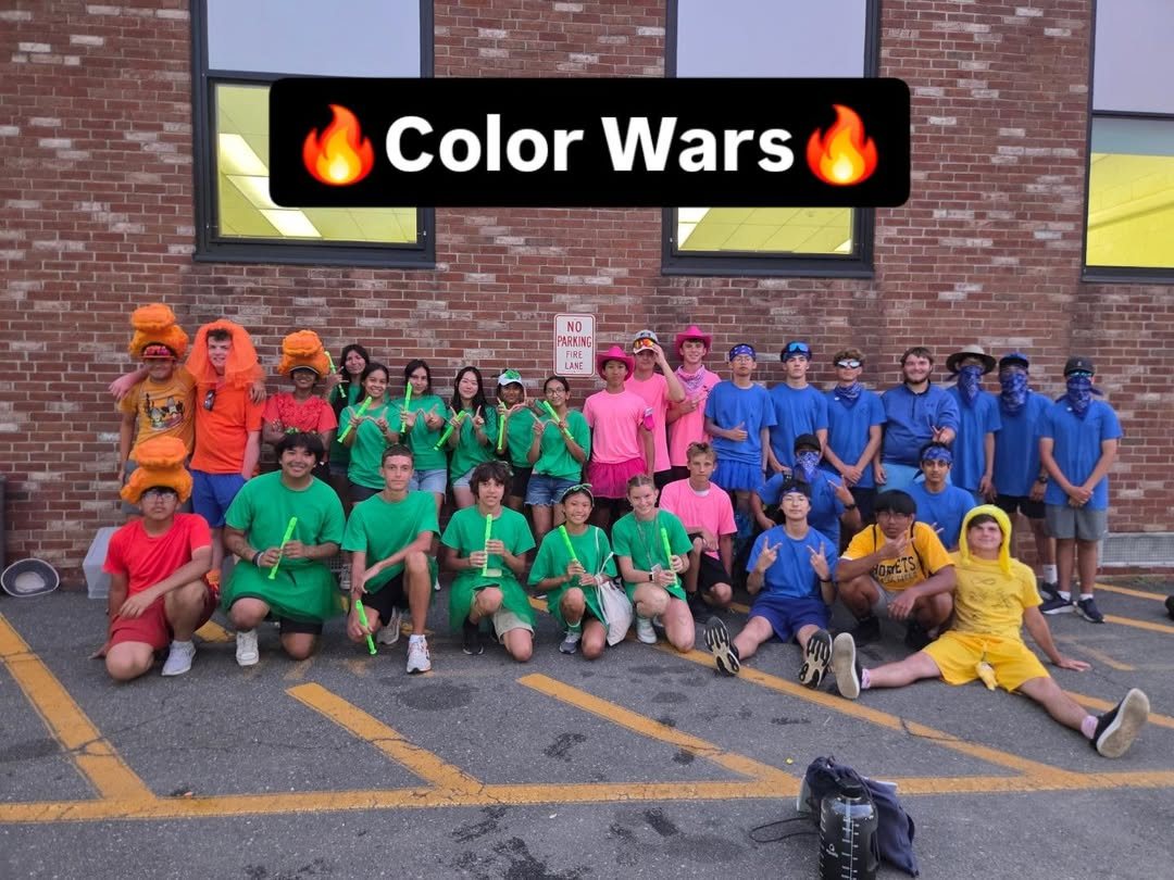 Band members in colored shirts and silly hats posing for Color Wars