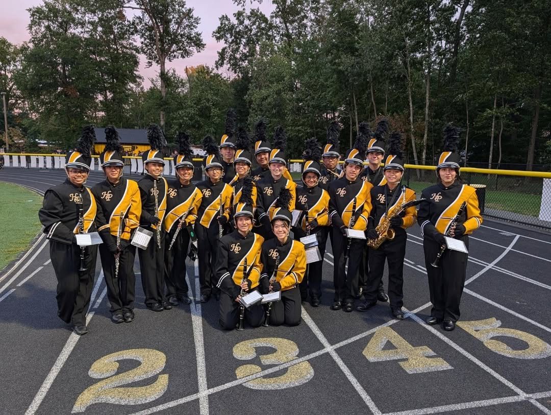 Clarinet and flute players in uniform kneeling and standing on the track