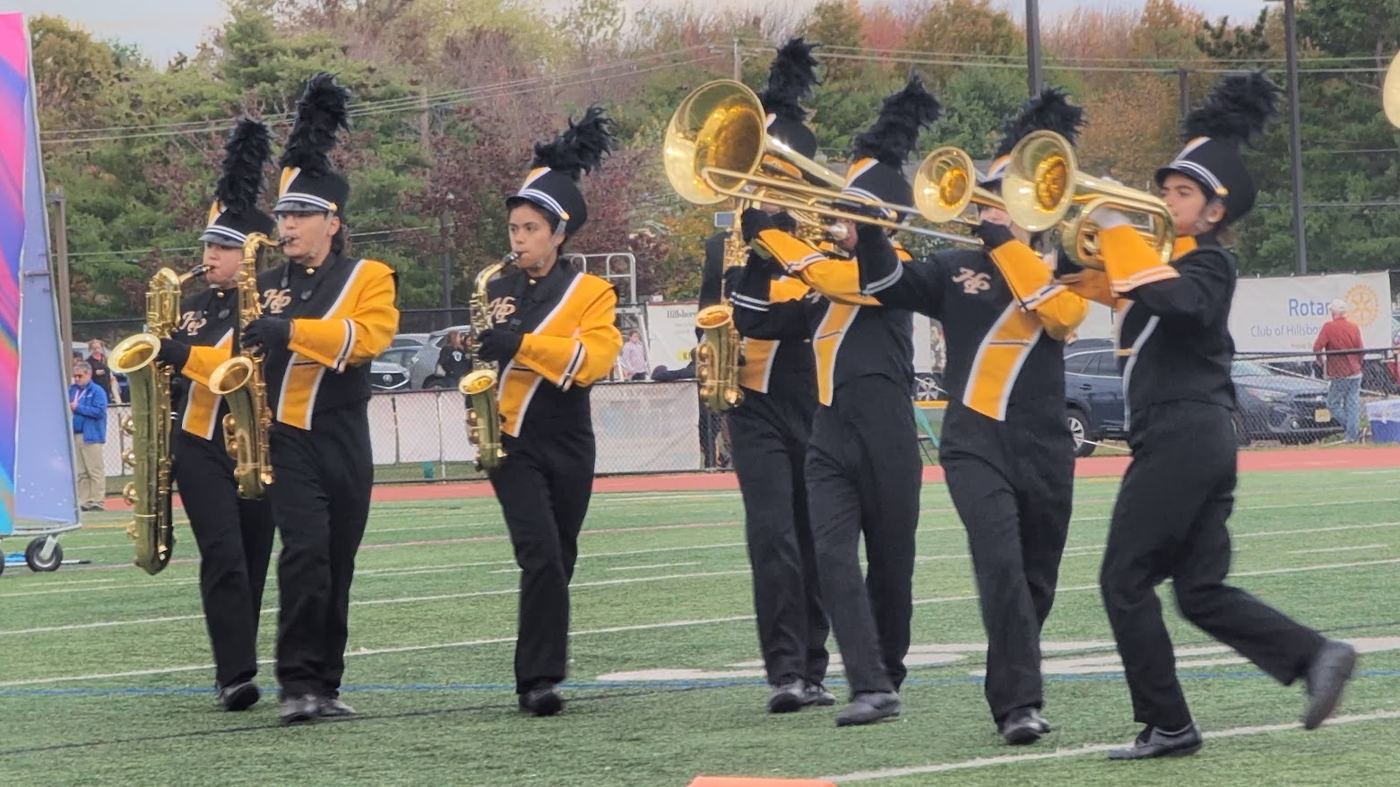 Saxophone and trombone players marching across the field