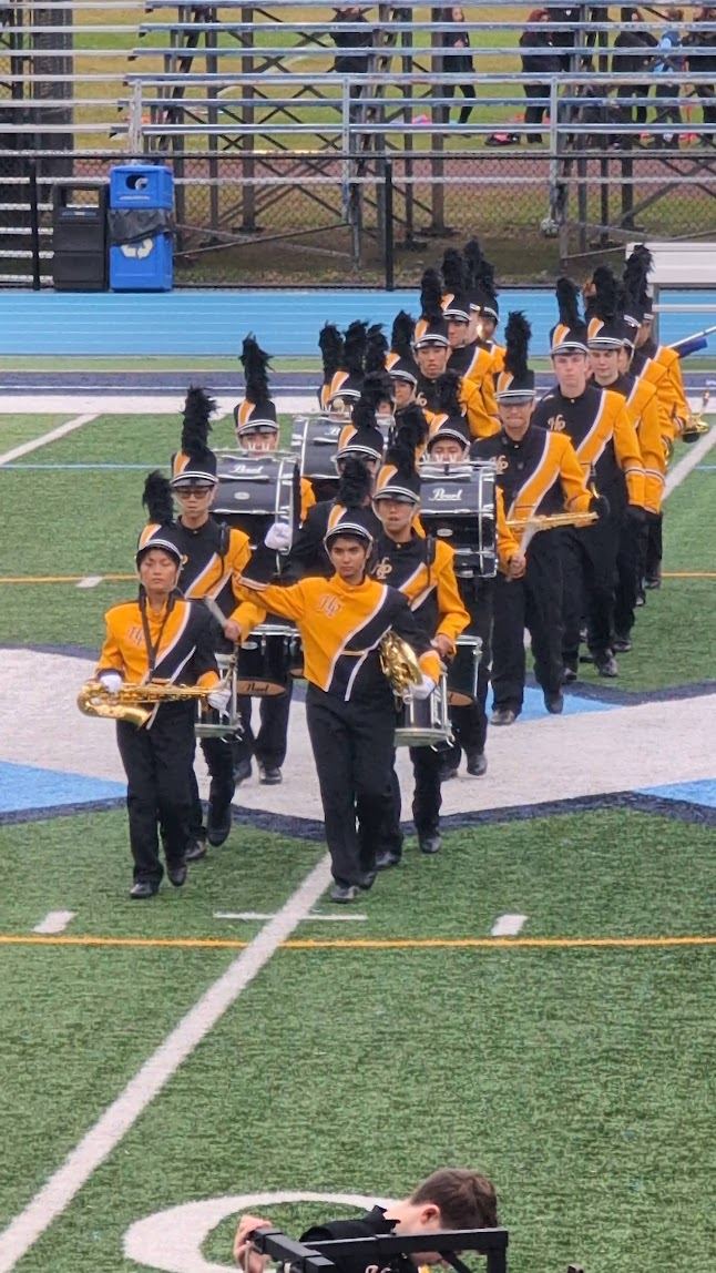 Drumline and horn players marching onto the field in rows