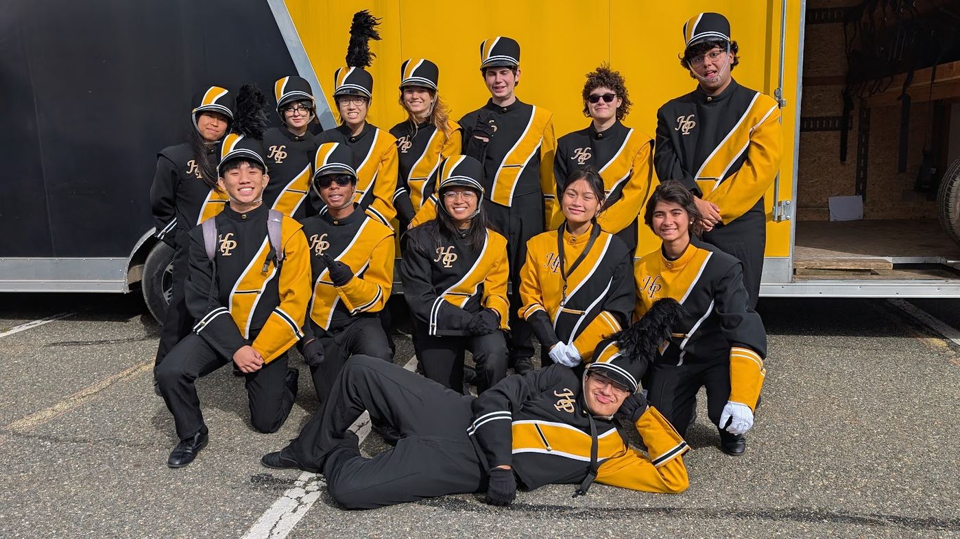 Band members smiling for a group photo in front of a yellow trailer