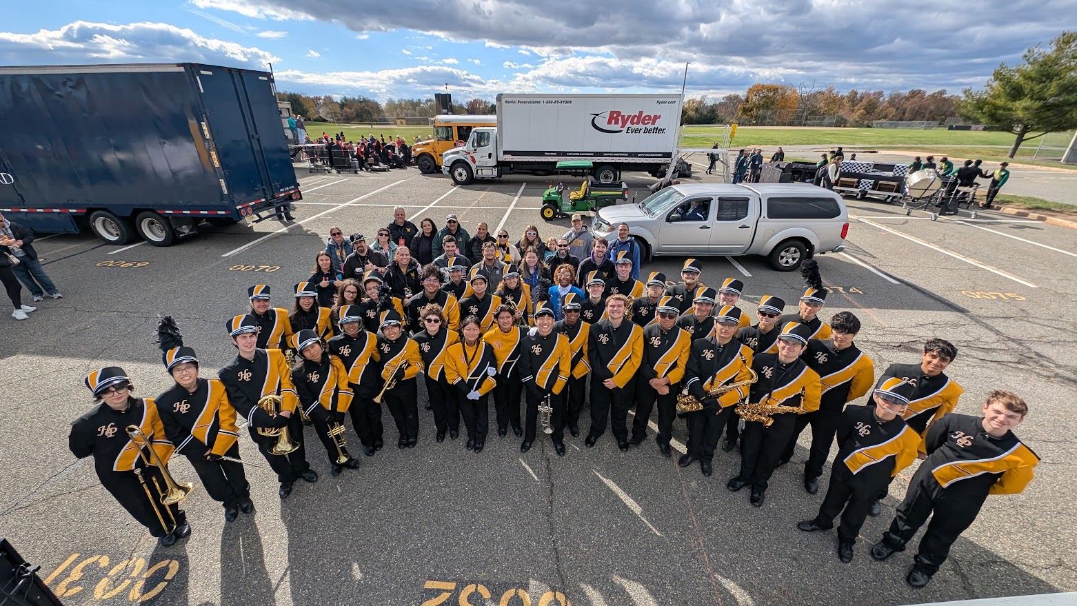 The Hanover Park Golden Hornets marching band in uniform, with parents standing behind them